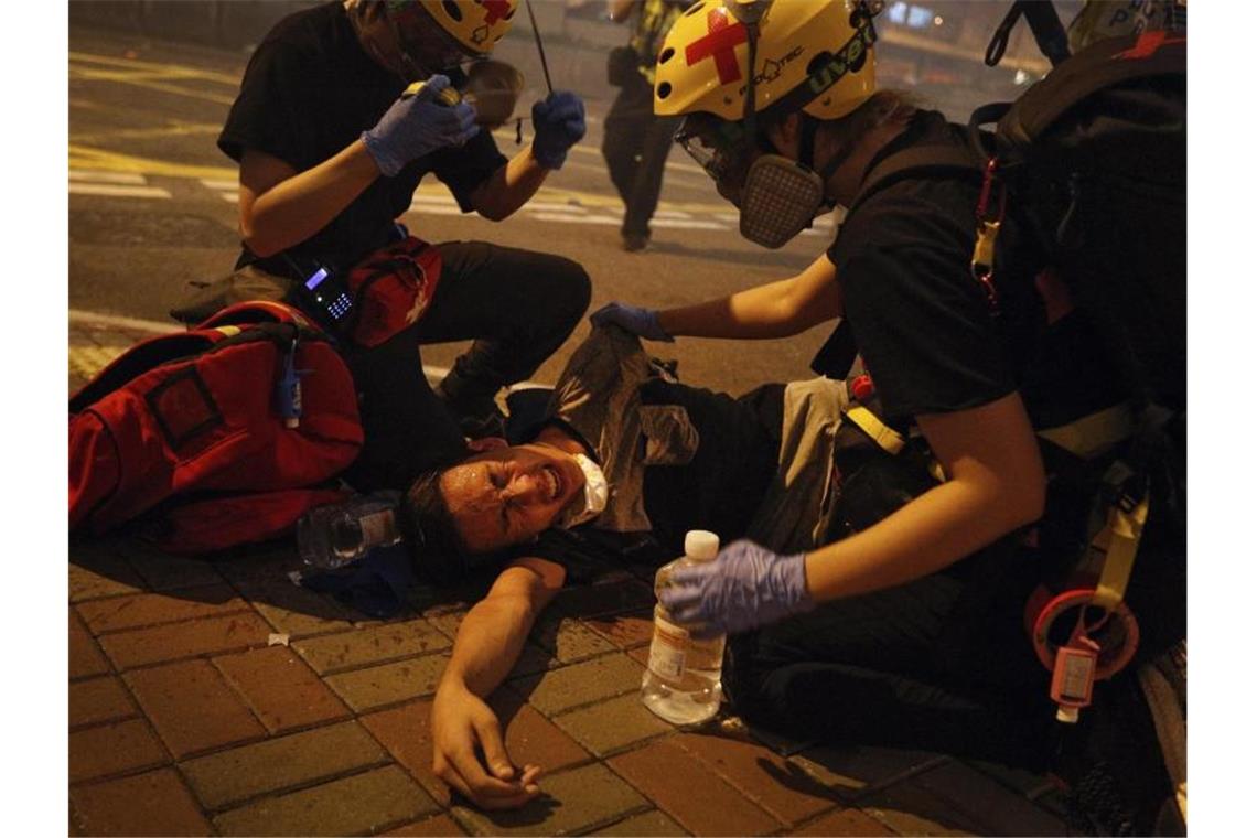 Hunderte Hongkonger protestieren am Airport gegen Regierung Sanitäter helfen einem von Tränengas getroffenen Demonstranten. Foto: Bobby Yip/AP