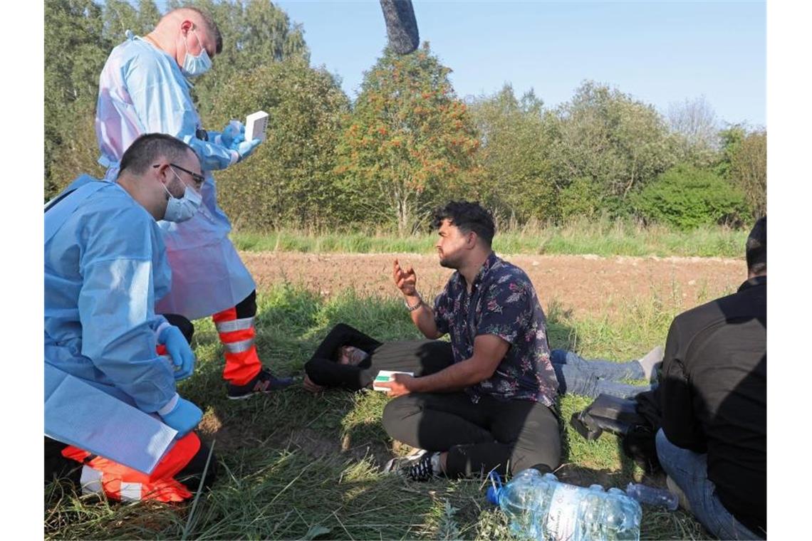 Sanitäter sprechen mit der Gruppe von Flüchtlingen an der polnisch-belarussischen Grenze. Foto: Artur Reszko/PAP/dpa