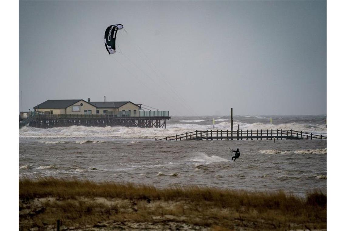 Orkane überqueren Deutschland Sankt Peter-Ording: Ein Kitesurfer zieht in dem vom Wind aufgepeitschten Meer seine Bahnen (Archivbild). Foto: Axel Heimken/dpa