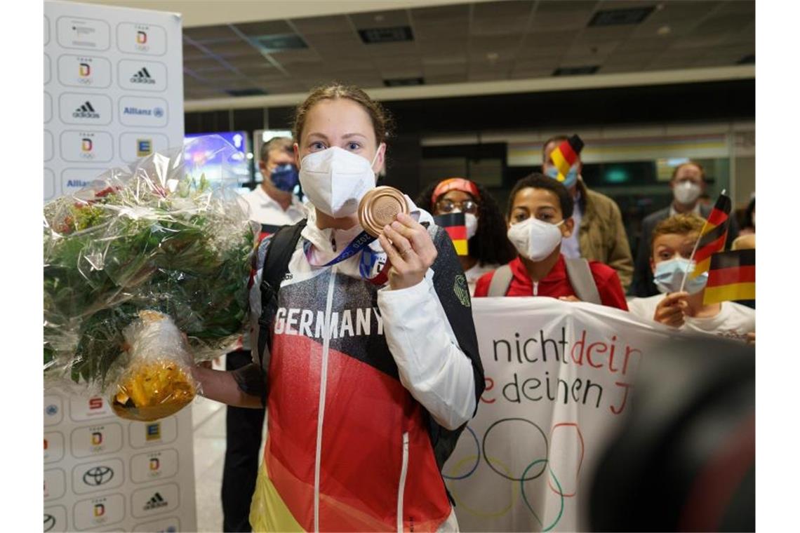 Sarah Köhler steht mit ihrer Bronzemedaille nach ihrer Ankunft aus Tokio auf dem Frankfurter Flughafen. Foto: Frank Rumpenhorst/dpa