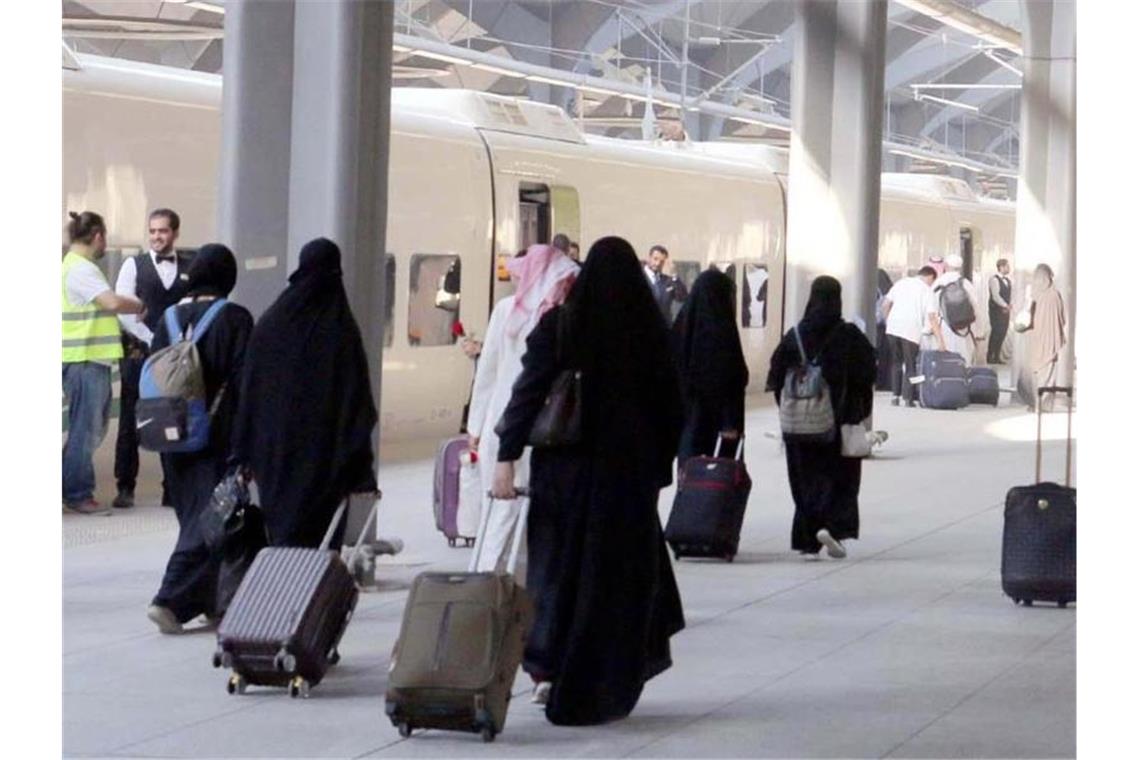 Saudische Frauen mit Ganzkörperschleier ziehen ihre Rollkoffer über einen Bahnsteig in Medina. Foto: SPA