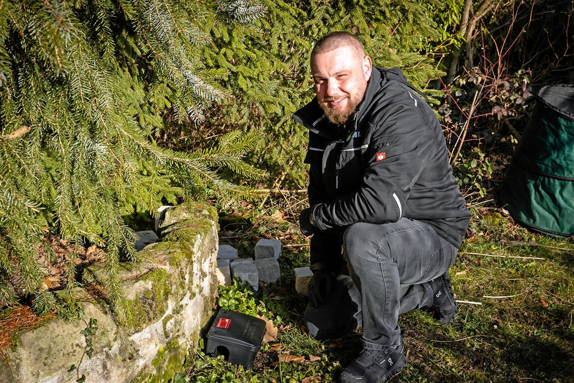 Schädlingsbekämpfer Adrian Machal bestückt eine Rattenfalle mit dem Giftköder und platziert sie in einem Garten. Foto: Alexander Becher