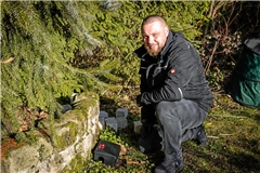 Schädlingsbekämpfer Adrian Machal bestückt eine Rattenfalle mit dem Giftköder und platziert sie in einem Garten. Foto: Alexander Becher