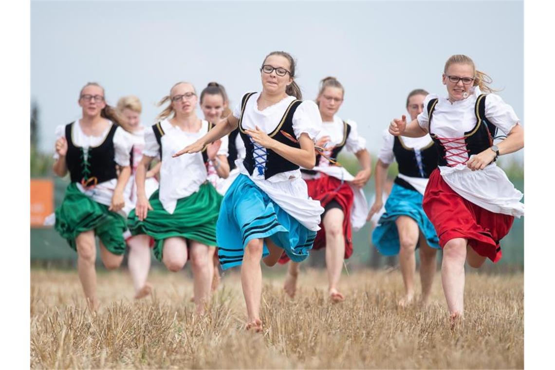 Schäfermädchen rennen während eines Schäferlaufs über ein Stoppelfeld. Foto: Sebastian Gollnow/dpa/Archivbild