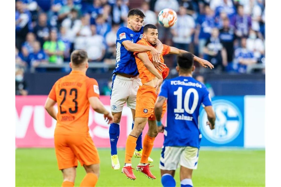 Schalkes Mehmet Aydin (2.v.l.) und Aues Soufiane Messequem (2.v.r.) gehen zum Kopfballduell hoch. Foto: Marcel Kusch/dpa