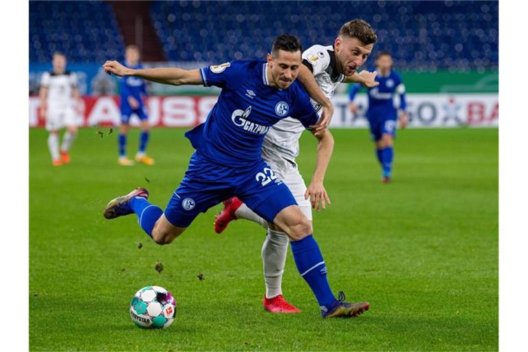 Schalkes Steven Skrzybski (l) und Ulms Albano Gashi kämpfen um den Ball. Foto: Guido Kirchner/dpa