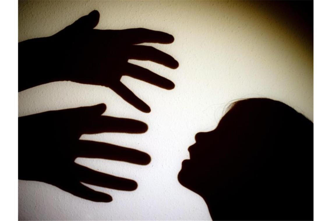 Schatten von Händen einer erwachsenen Person und dem Kopf eines Kindes. Foto: Patrick Pleul/zb/dpa