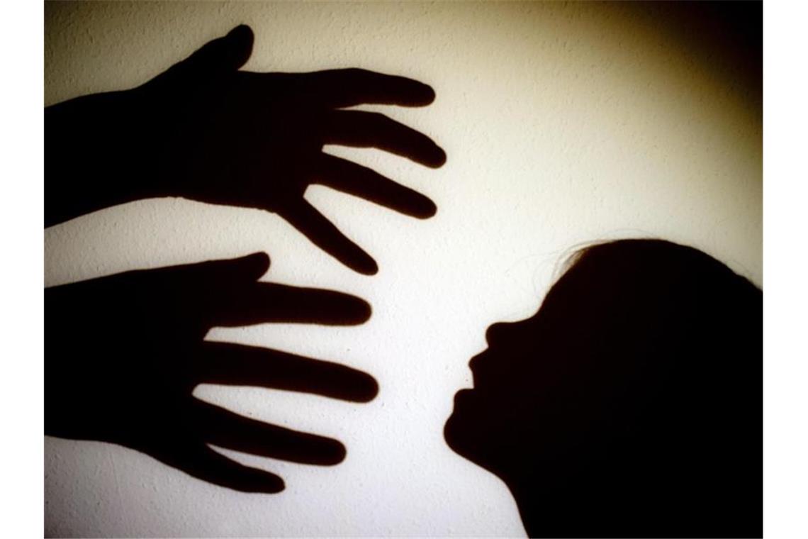 Schatten von Händen einer erwachsenen Person und dem Kopf eines Kindes an einer Wand eines Zimmers. Foto: Patrick Pleul/dpa-Zentralbild/dpa/Illustration