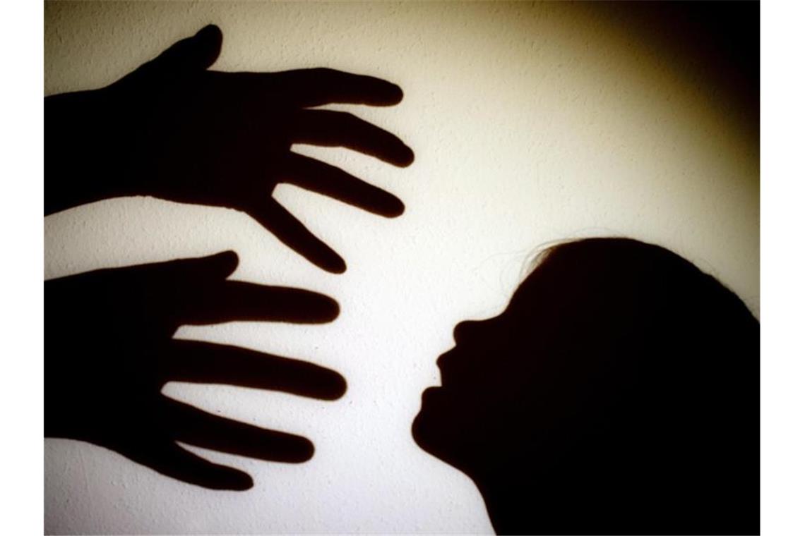 Schatten von Händen einer erwachsenen Person und dem Kopf eines Kindes an einer Wand. Foto: Patrick Pleul/zb/dpa/Symbolbild