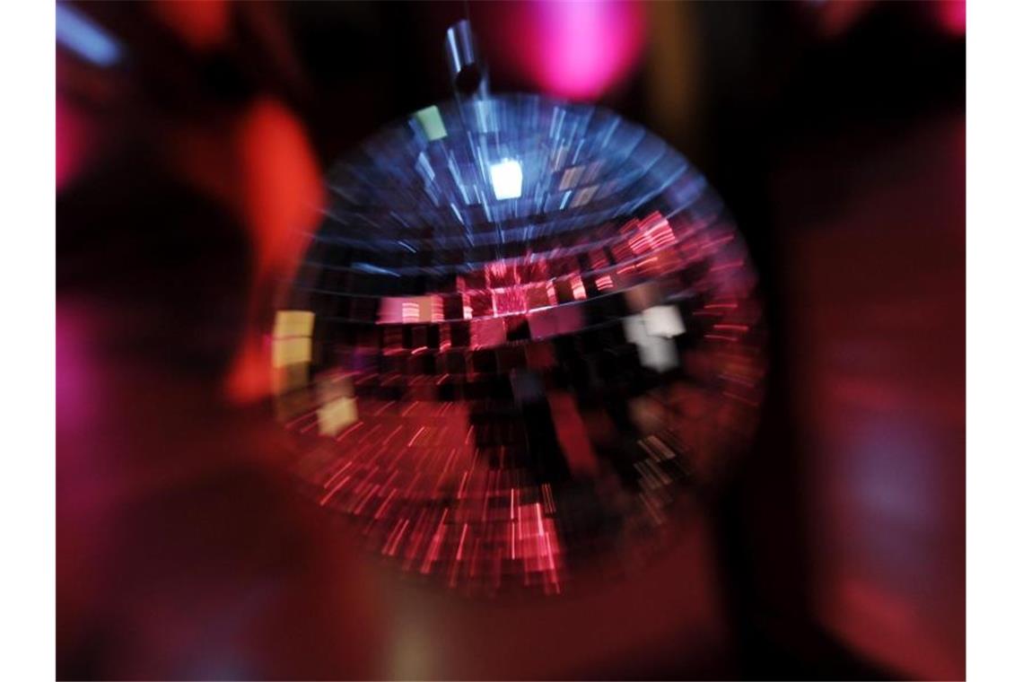 Scheinwerferlicht spiegelt sich in einer Discokugel. Foto: picture alliance / dpa/Symbolbild
