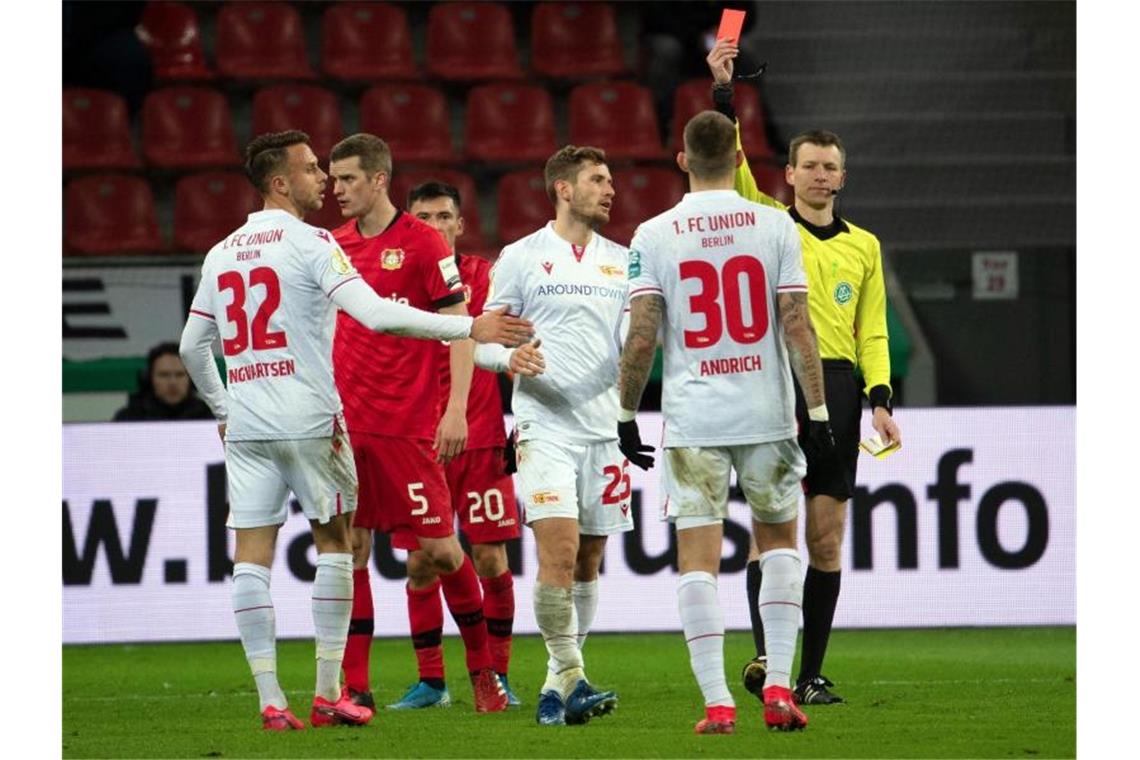 Leverkusen nach Rückstand im Pokal-Halbfinale Schiedsrichter Benjamin Cortus (r) zeigt Berlins Christopher Lenz (3.v.r.) die gelb-rote Karte. Foto: Federico Gambarini/dpa