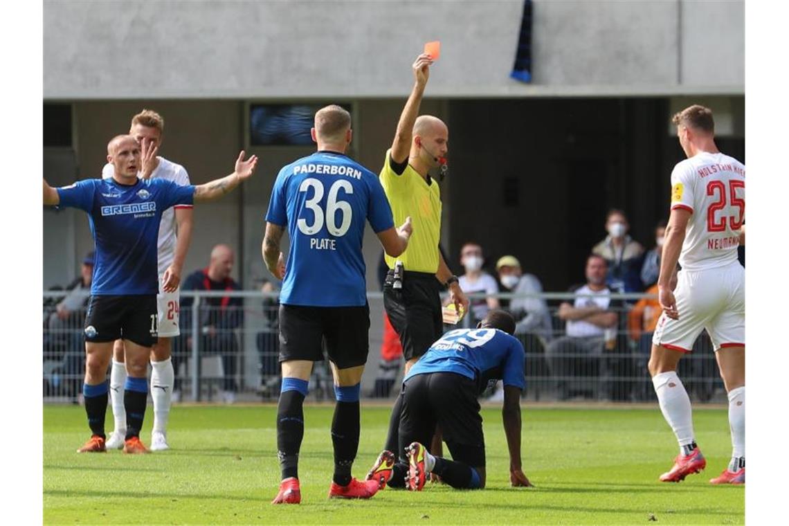 Überraschungsteams an der Spitze - HSV und Bremen patzen Schiedsrichter Franz Boskop (M) zeigt Paderborns Jamilu Collins (2.v.r/unten) die Gelb-Rote Karte. Foto: Friso Gentsch/dpa