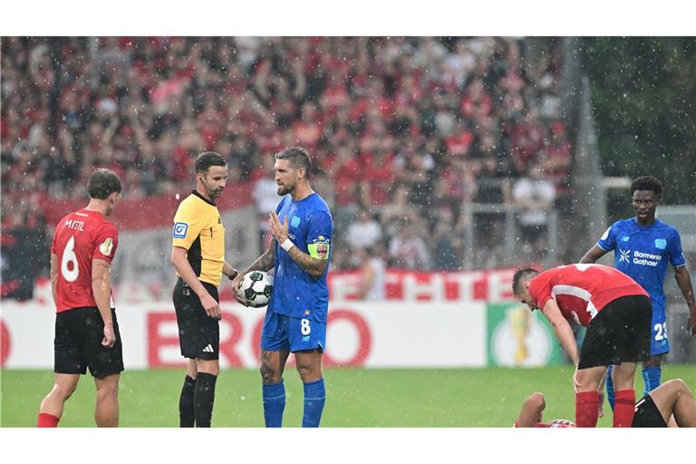 Schiedsrichter Michael Bacher (2.v.l.) muss das Spiel in Großaspach unterbrechen