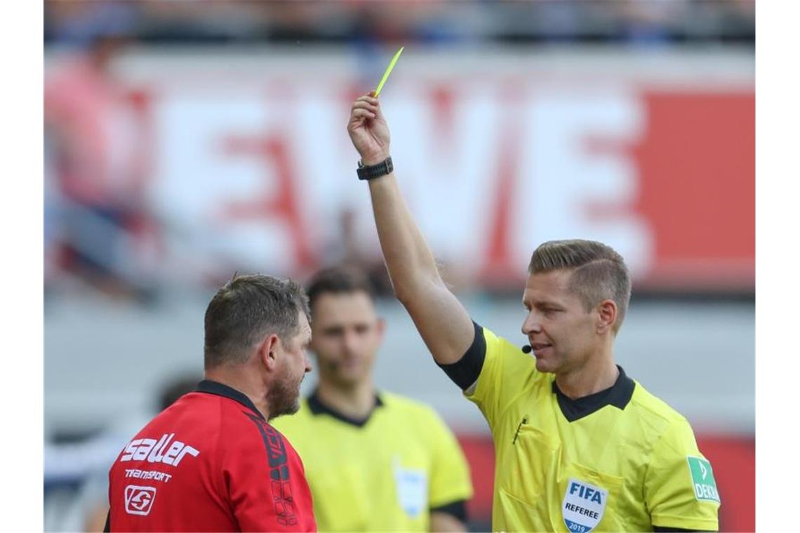 Schiedsrichter Tobias Welz (r) zeigt Paderborn-Trainer Baumgart (l) die erste Gelbe Karte. Foto: Friso Gentsch