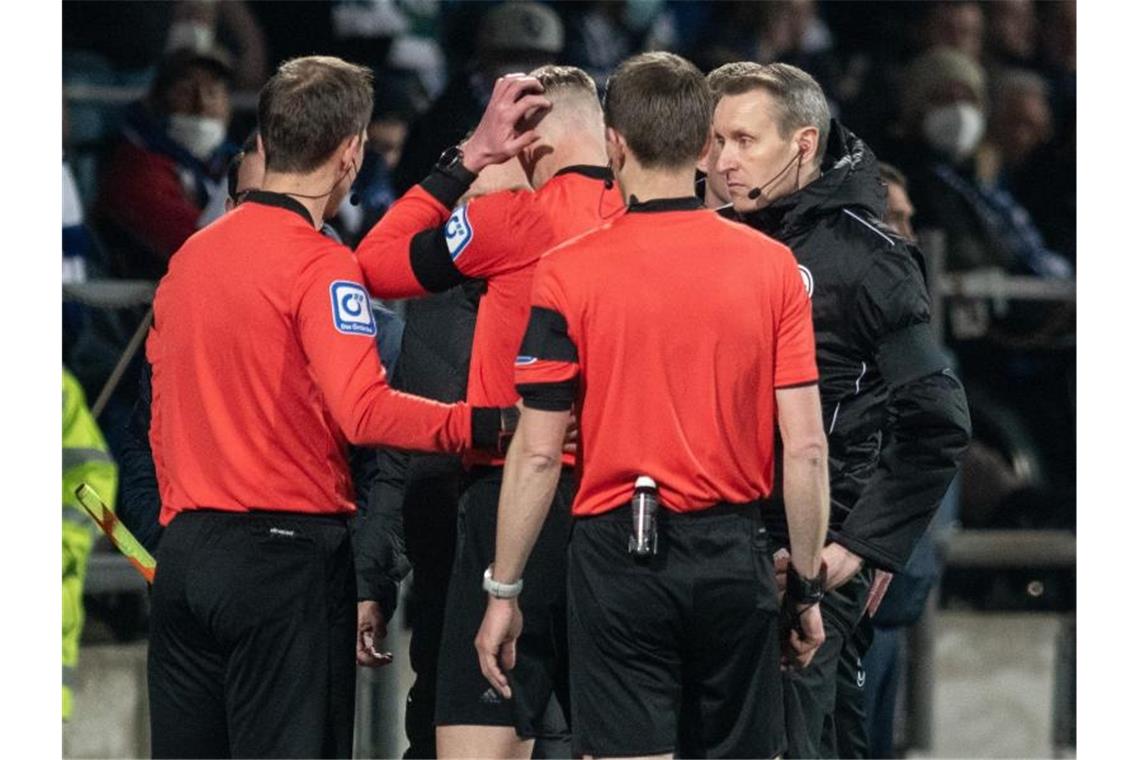 Nach Becherwurf: Spiel Bochum gegen Gladbach abgebrochen Schiedsrichterassistent Christian Gittelmann (M) wurde in Bochum von einem Bierbecher getroffen. Foto: Bernd Thissen/dpa