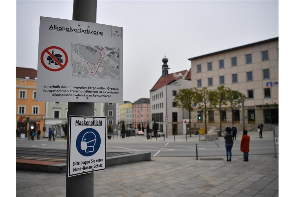 Schilder weisen am Ludwigsplatz auf die bestehende Alkoholverbotszone und die Maskenpflicht in Passau hin. Foto: Lino Mirgeler/dpa