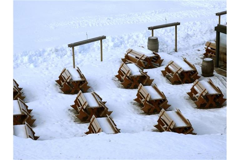Schnee bedeckt Bänke und Tische an einer gesperrten Skipiste. Die österreichische Regierung hatte die Schließung der Skigebiete angeordnet, um die Ausbreitung des Coronavirus zu verlangsamen. Foto: Matthias Schrader/AP/dpa
