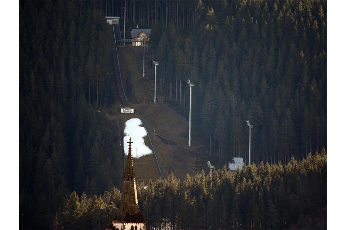 Skisprung-Quali in Titisee-Neustadt wird zur Farce Schnee liegt auf dem Auslauf der Hochfirstschanze vor dem Turm des Münsters St. Jakobus. Foto: Patrick Seeger/dpa/Archiv