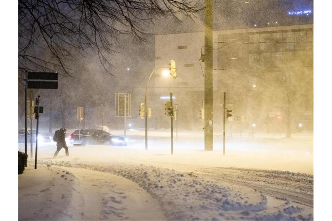 Schneegestöber und zugeschneite Straßen in Bielefeld. Dieser Mann wagt sich dennoch vor die Tür. Foto: Marcel Kusch/dpa