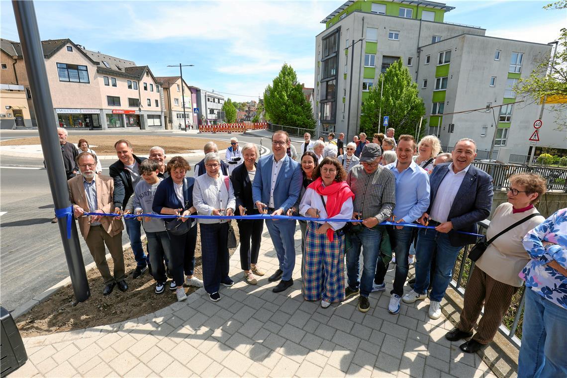 Wichtige Etappe für die Backnanger Stadtsanierung Schnipp, schnapp: Eine ganze Schar an Einweihungsgästen setzt mit Oberbürgermeister Maximilian Friedrich (Mitte, blaues Jackett) die Scheren an, um das blaue Band an der Aspacher Straße symbolisch zu durchtrennen. Foto: Alexander Becher
