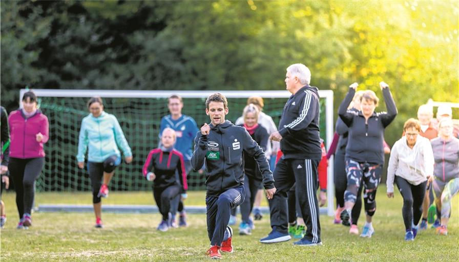 Schon das Aufwärmprogramm mit Marcel Fehr, Mittel- und Langstreckenläufer und Mitglied der Deutschen Nationalmannschaft (vorne), und seinem Trainer Uwe Schneider (stehend, in der Mitte) war ganz schön anstrengend und anspruchsvoll. Die beiden haben am Dienstagabend das Training der Laufend-BKZ-Gruppe geleitet. Foto: A. Becher
