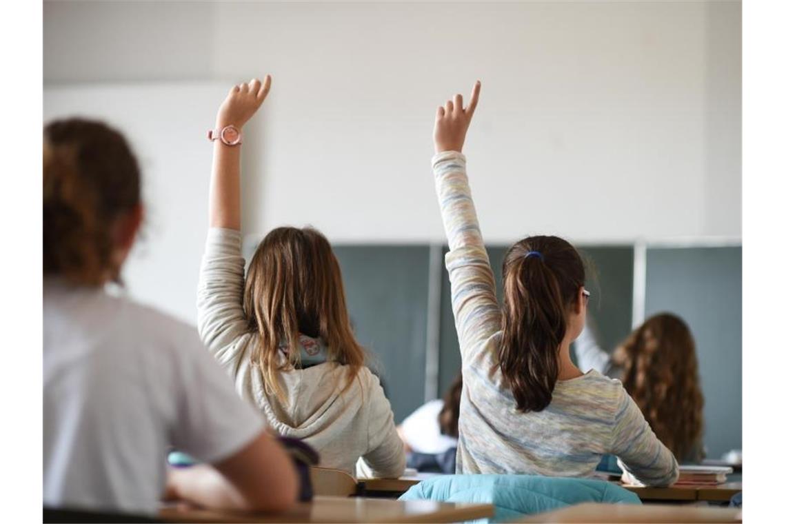 Schüler einer Klasse melden sich während des Unterrichts in einem Gymnasium. Foto: Felix Kästle/dpa/Archivbild