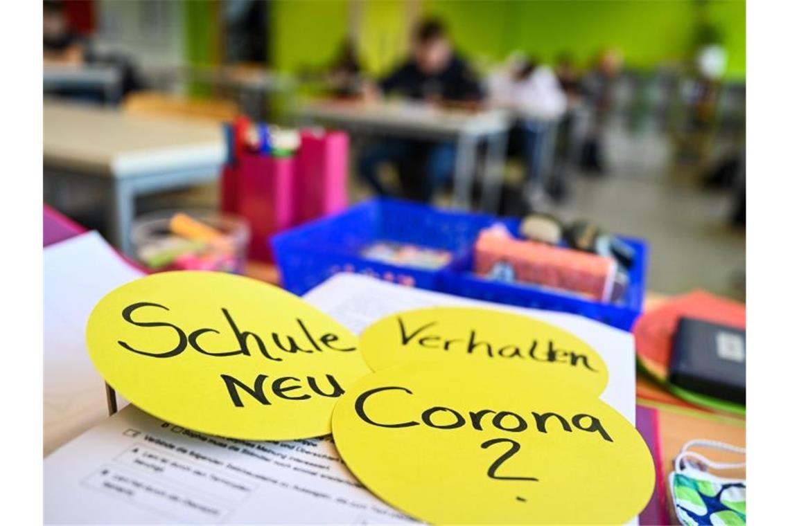 Schüler im Klassenzimmer und Papierschilder auf dem Lehrerpult. Foto: Felix Kästle/dpa/Archivbild