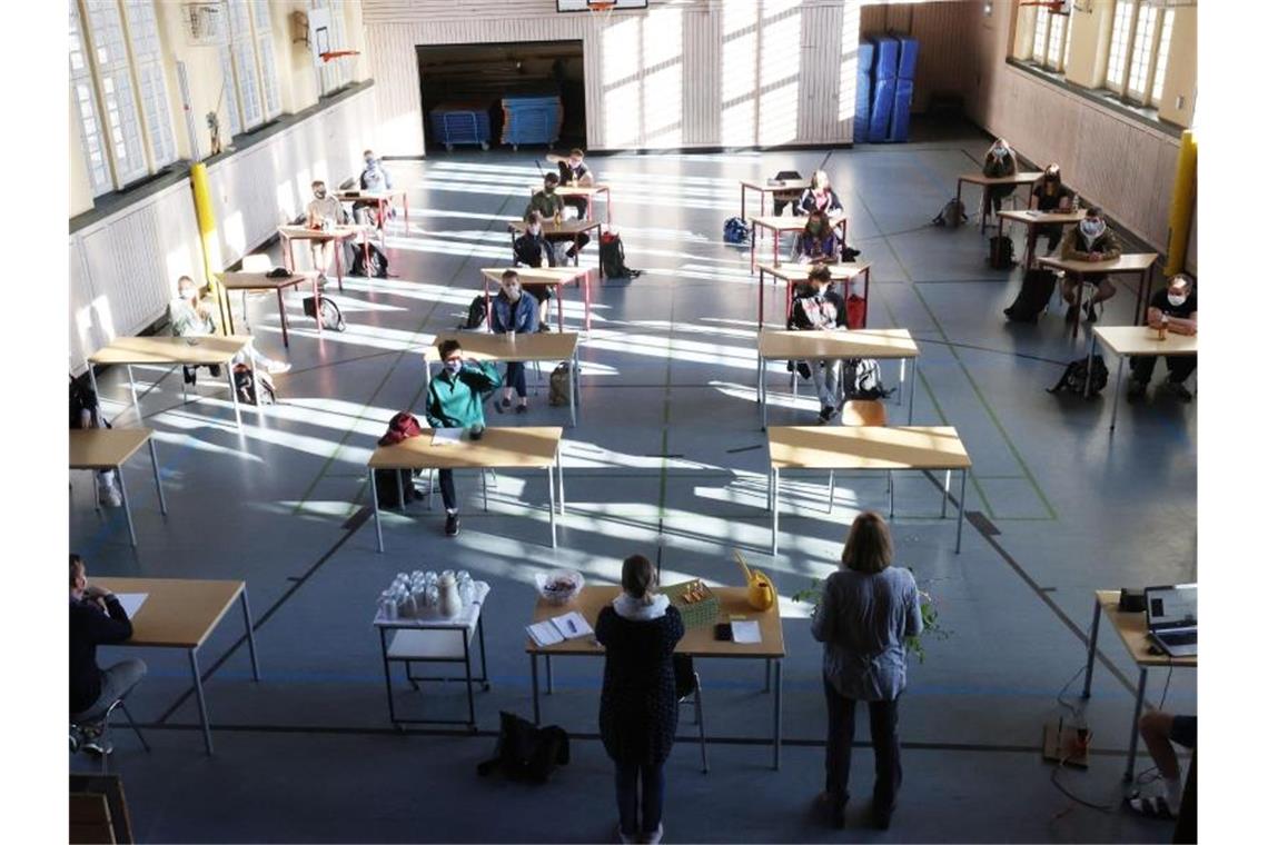 Schüler mit Mundschutz sitzen bei der Prüfungsvorbereitung fürs Abitur in einer Halle. Foto: Bodo Schackow/dpa-Zentralbild/dpa/Archivbild