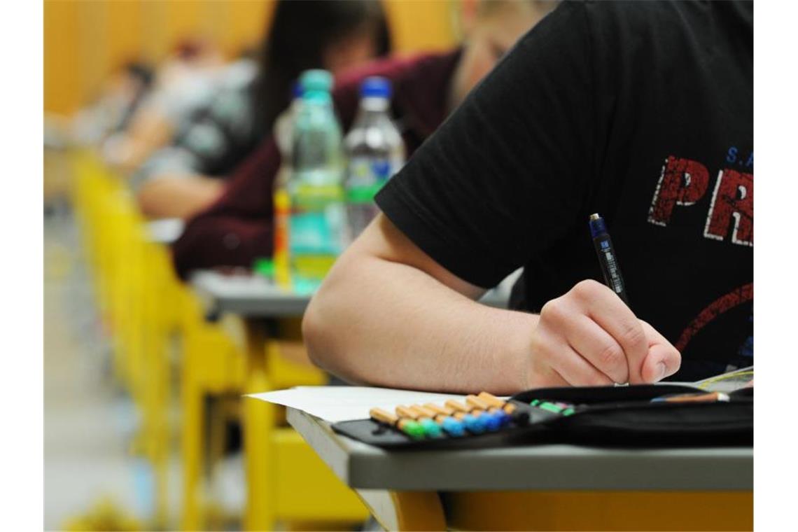 Schüler sitzen in Tischreihen hintereinander und schreiben. Foto: Armin Weigel/Archivbild