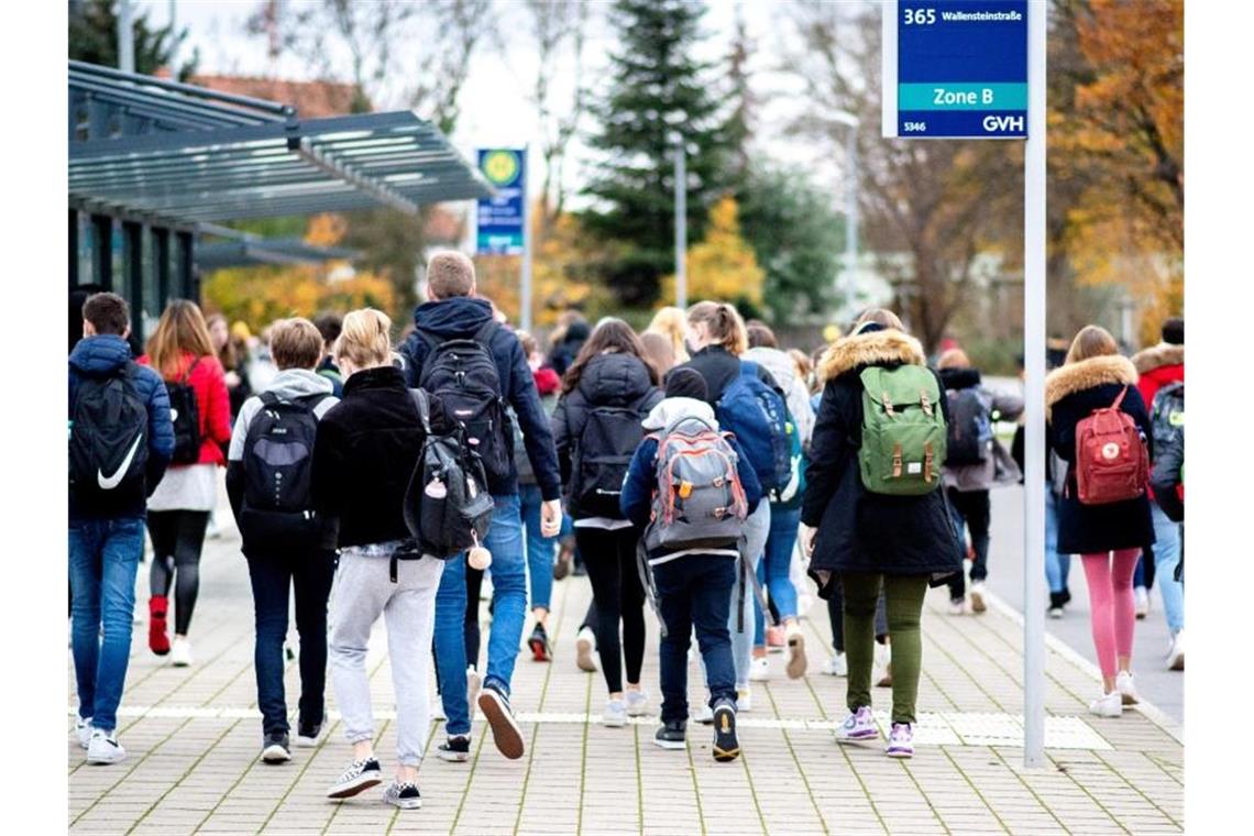 Schülerinnen und Schüler gehen mit ihren Schulrucksäcken von einer Bushaltestelle zu ihrer Schule in Niedersachsen. Foto: Hauke-Christian Dittrich/dpa