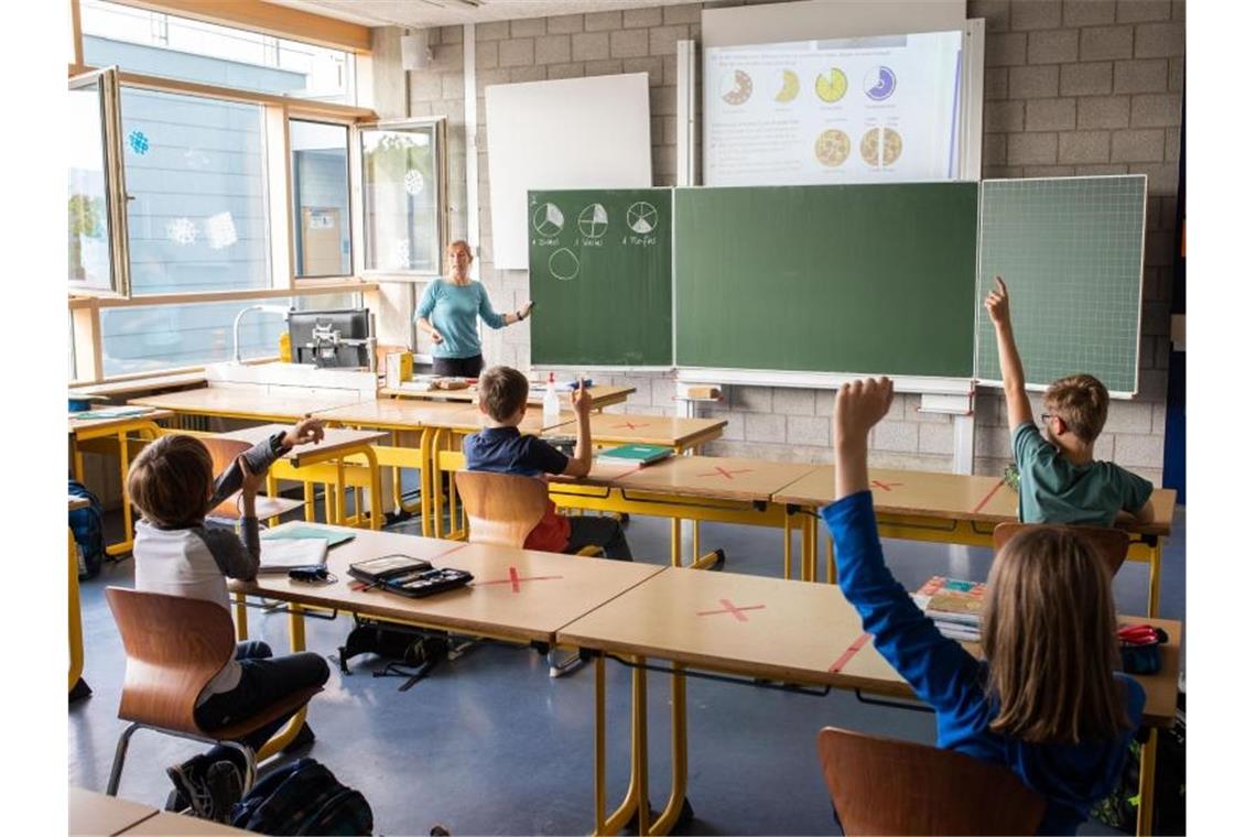 Krise im Klassenzimmer? Die größten Probleme im Schulalltag Schulkinder sitzen an ihren Tischen, während eine Lehrerin an der Tafel unterrichtet. Foto: Philipp von Ditfurth/dpa/Archivbild
