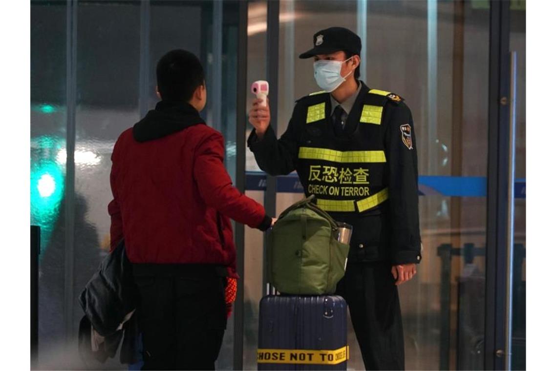 Schutzmaßnahme gegen die Verbreitung des Corona-Virus: Ein Beamter misst am Flughafen von Wuhan die Körpertemperatur von Reisenden. Foto: Dake Kang/AP/dpa