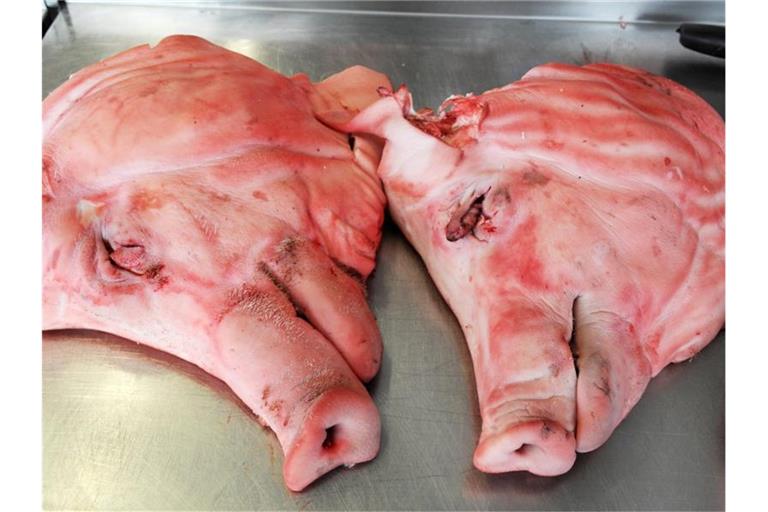 Schweineköpfe liegen auf einem Tisch. Foto: Waltraud Grubitzsch/dpa-Zentralbild/dpa/Archivbild