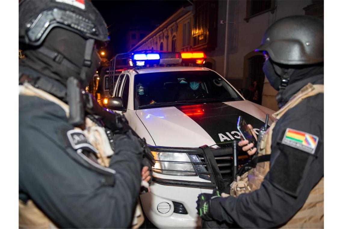 Haftbefehl gegen Boliviens Ex-Übergangspräsidentin Áñez Schwerbewaffnete Polizisten bewachen zwei ehemalige Minister auf ihrem Weg zur Aussage. Foto: Radoslaw Czajkowski/dpa