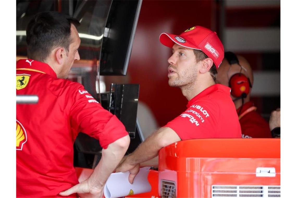 Vettel über möglichen Rücktritt: „Keine Option“ Sebastian Vettel (r) aus Deutschland vom Team Scuderia Ferrari spricht mit einem Renningenieur in der Box. Foto: Jan Woitas