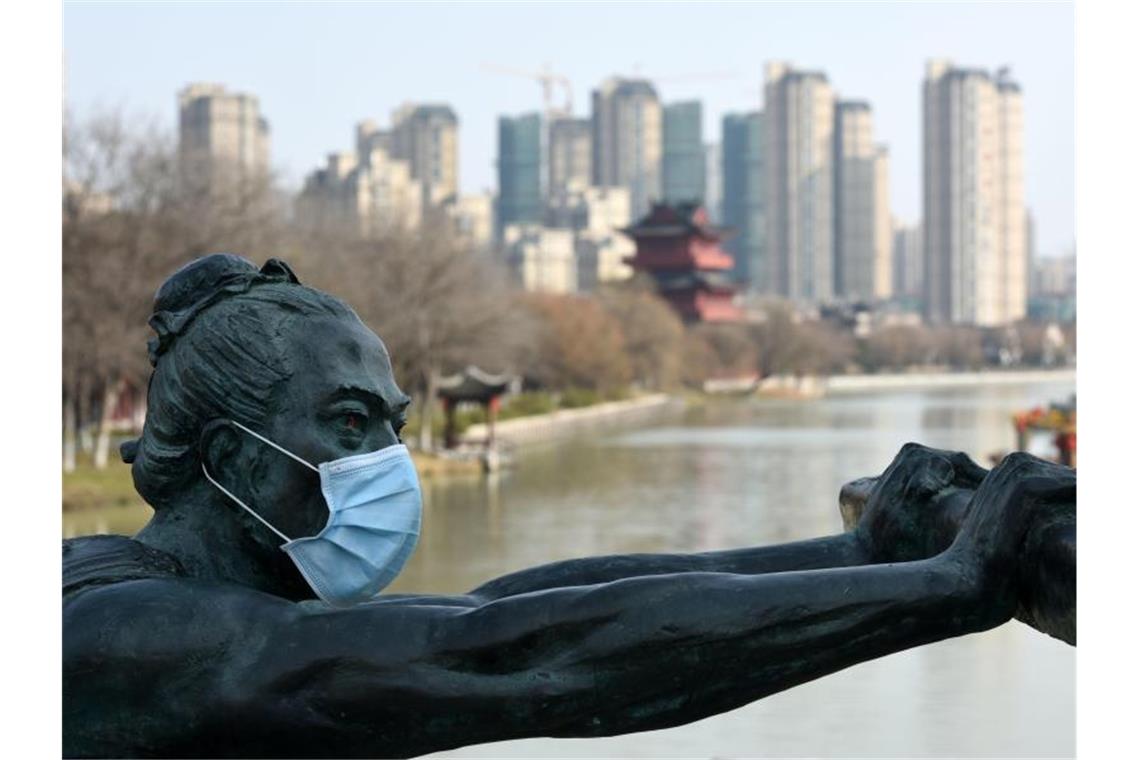 Selbst eine Statue vor der Skyline der Stadt Huai'an in Ostchina trägt eine Atemschutzmaske. Foto: He Jinghua/SIPA Asia via ZUMA Wire/dpa
