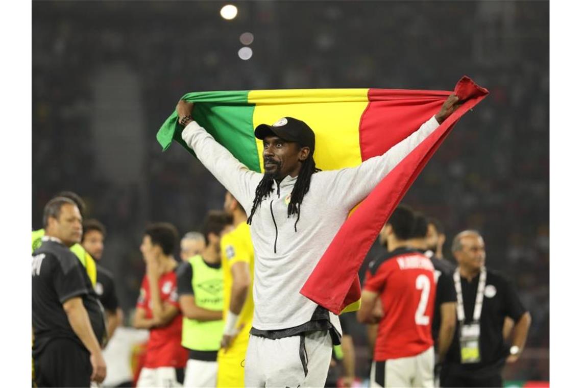 Senegals Trainer Aliou Cissé feiert mit der Nationalflagge den Sieg. Foto: Ayman Aref/dpa