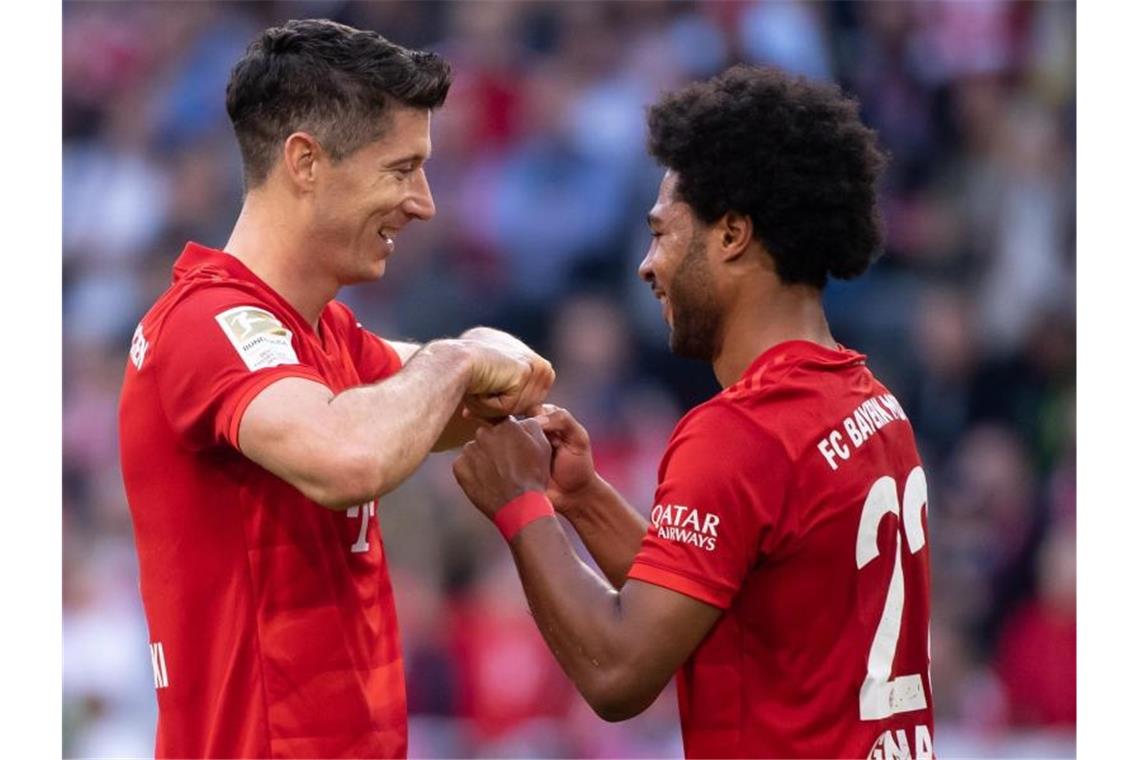 Serge Gnabry (r) gratuliert seinem Bayern-Kollegen Robert Lewandowski zum Torrekord. Foto: Sven Hoppe/dpa