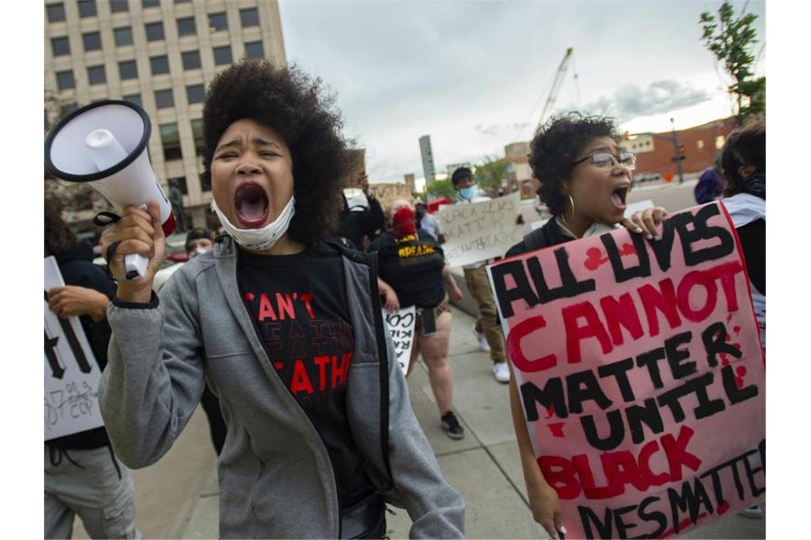 Shayana Dabney (l.) führt während eines Protestes in Colorado Springs eine Gruppe von Demonstranten mit einem Megafon durch die Innenstadt. Foto: Christian Murdock/The Gazette/AP/dpa
