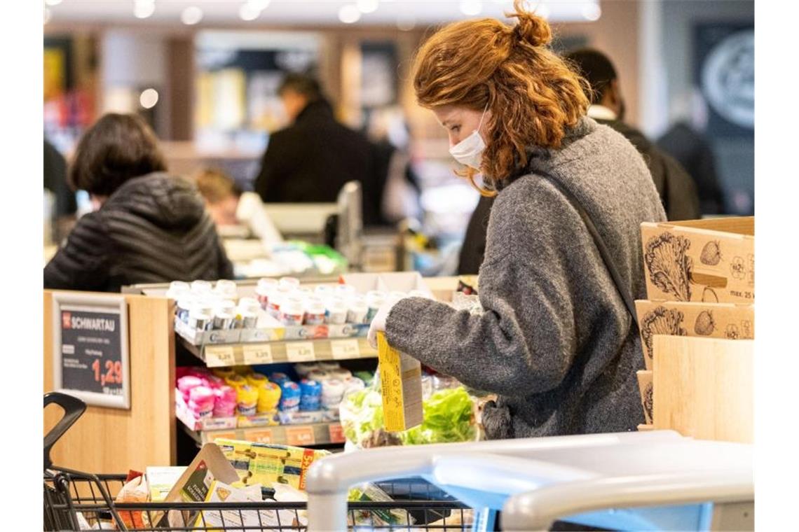 Sicher ist sicher: Mit einer Schutzmaske kauft eine Frau in einem Supermarkt ein. Foto: Peter Steffen/dpa