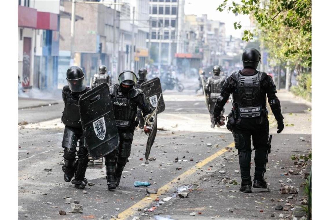 Sicherheitskräfte in einer mit Steinen und Scherben bedeckten Straße der Hauptstadt. F. Foto: Juan Diego Montenegro/dpa