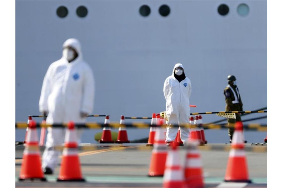 Sicherheitskräfte stehen in Yokohama vor der „Diamond Princess“. Das Schiff hatte wegen des neuartigen Coronavirus Sars-CoV-2 zwei Wochen lang unter Quarantäne gestanden. Foto: Eugene Hoshiko/AP/dpa