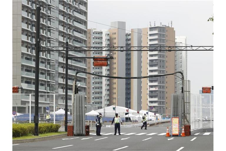 Sicherheitskräfte stehen vor dem Olympischen Dorf in Tokio. Foto: ---/Kyodo/dpa