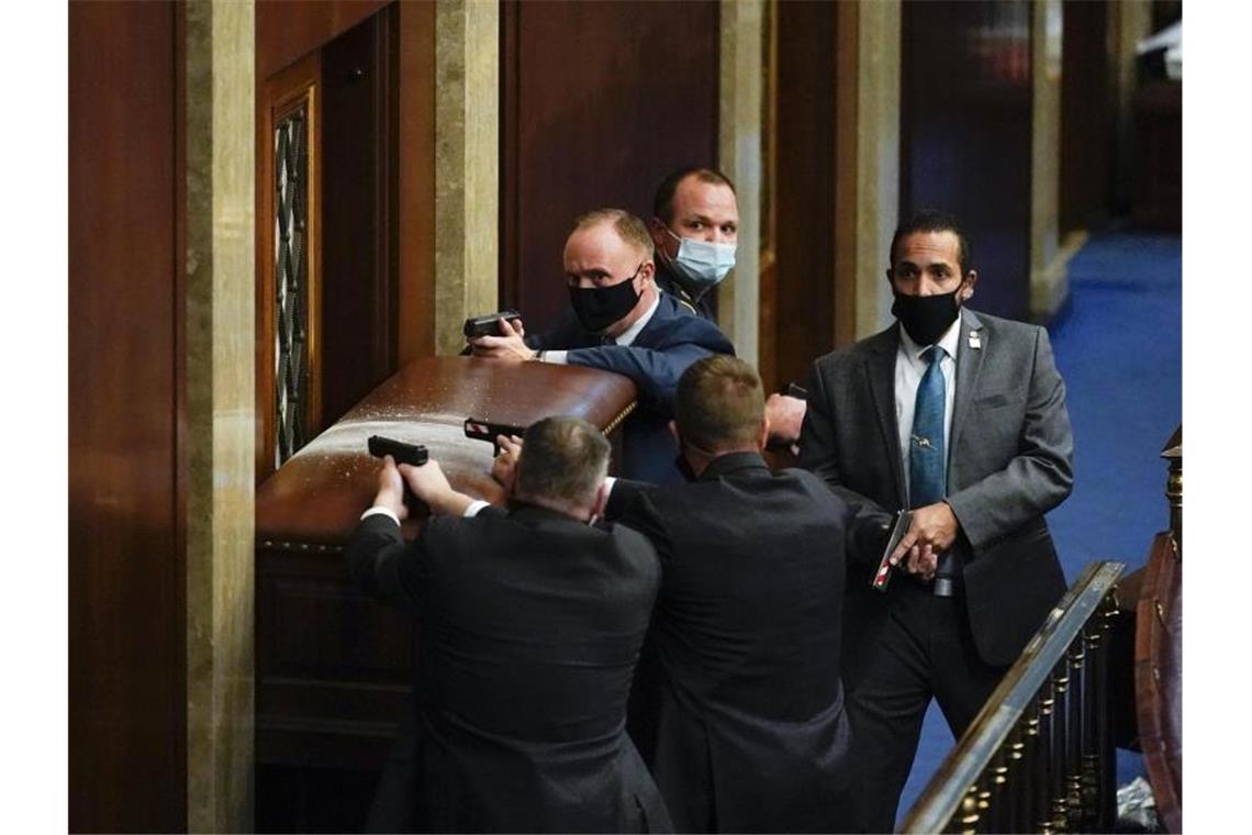 Sicherheitsleute des Kapitols stehen mit gezogenen Waffen hinter einer verbarrikadierten Tür. Foto: Andrew Harnik/AP/dpa