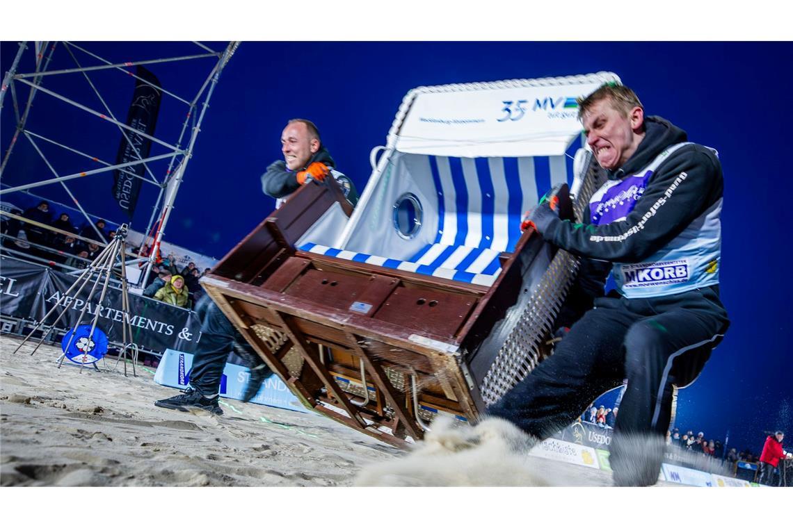Sie geben alles: Das Team „Quad Safari Usedom“ mit Phillip Schmidt (l) und Finley Liemen (r) gewinnt den Finallauf bei der 18. Strandkorb Weltmeisterschaft auf der Insel Usedom mit einer neuen Weltrekordzeit von 4,56 Sekunden. Die Zweierteams müssen bei dem Wettkampf einen etwa 60 Kilogramm schweren Strandkorb über die 20 Meter lange Strecke über den Ostseestrand ins Ziel schleppen.