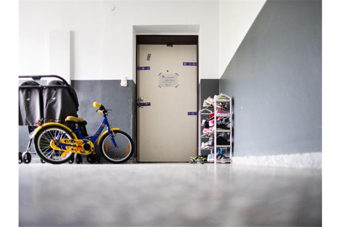Siegel der Polizei hängen an einer Wohnungstür in einem Mehrfamilienhaus, davor stehen ein Kinderwagen, ein Kinderrad und ein Schuhregal. Eine 27 Jahre alte Mutter soll hier fünf Kinder umgebracht haben. Foto: Marcel Kusch/dpa