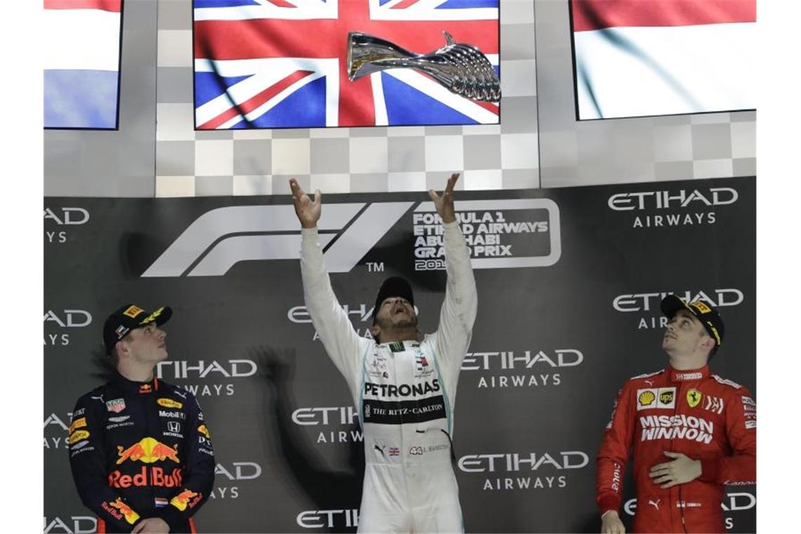 Sieger Lewis Hamilton (M) wirft den Pokal zwischen Max Verstappen (l) und Charles Leclerc in die Höhe. Foto: Luca Bruno/AP/dpa