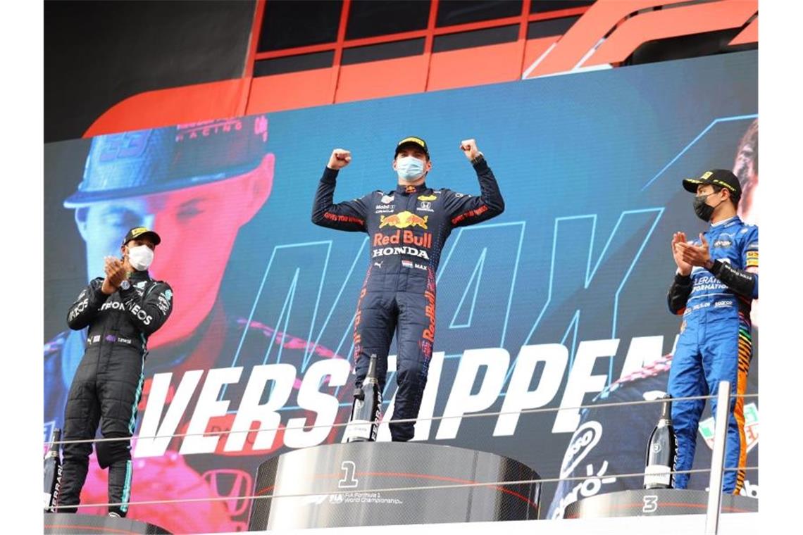 Sieger Max Verstappen (M) steht mit dem Zweitplatzierten Lewis Hamilton (l) und dem Drittplatzierten Lando Norris auf dem Podium. Foto: Bryn Lennon/AP/dpa