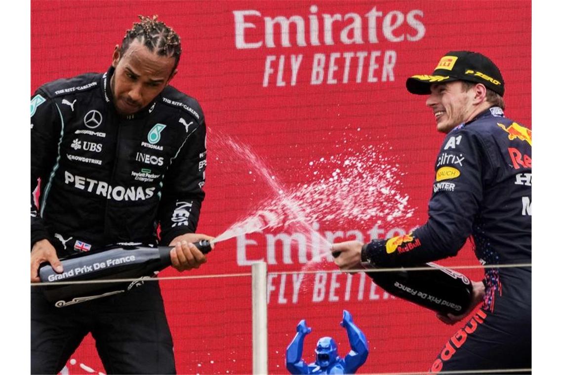 Sieger Max Verstappen (r) und der Zweitplatzierte Lewis Hamilton lassen auf dem Podium den Champagner spritzen. Foto: Francois Mori/AP/dpa