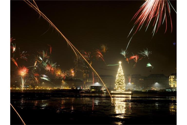 Silvesterraketen erleuchten den Himmel über der Binnenalster in Hamburg. Foto: Angelika Warmuth/dpa/Archiv